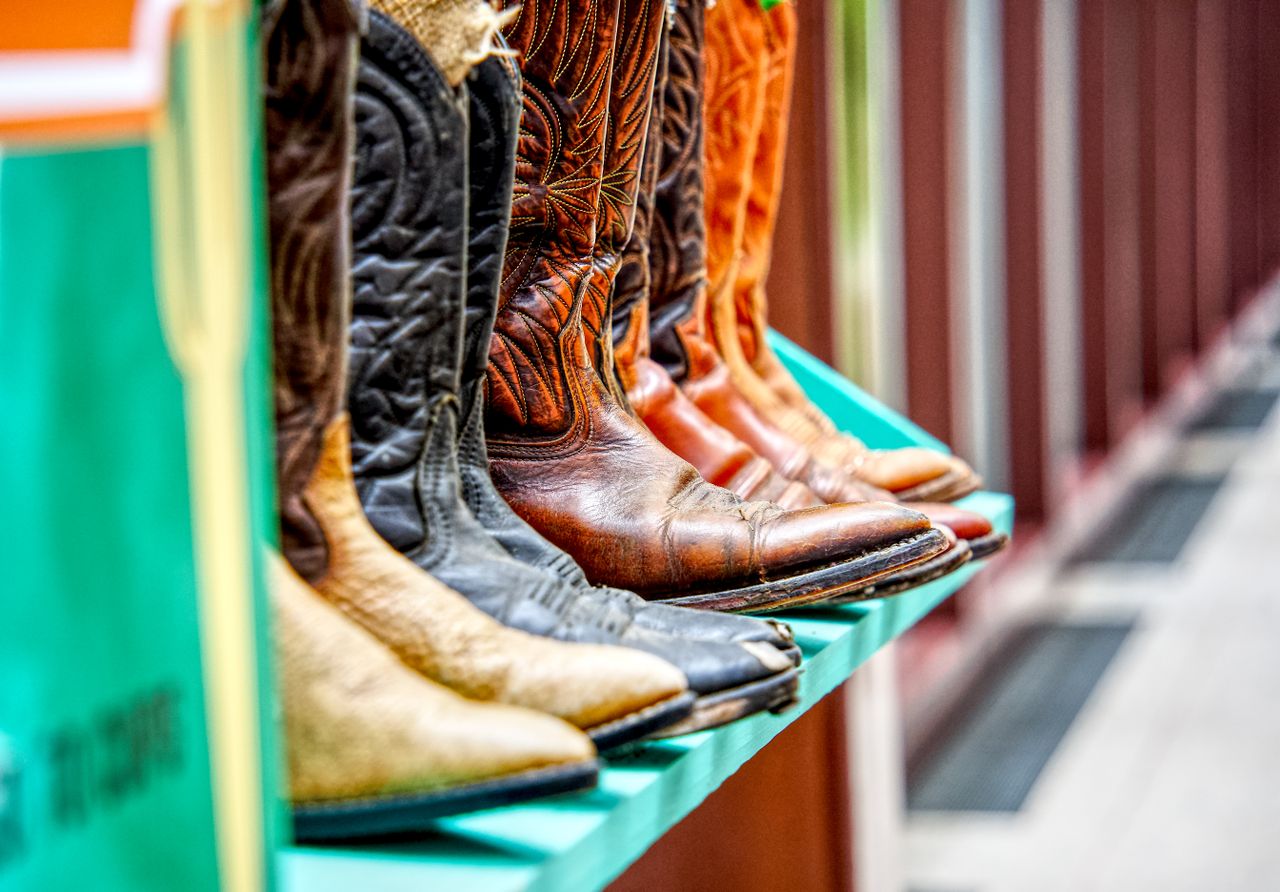 Colorful display of leather cowboy boots on a shelf, showcasing detailed craftsmanship.