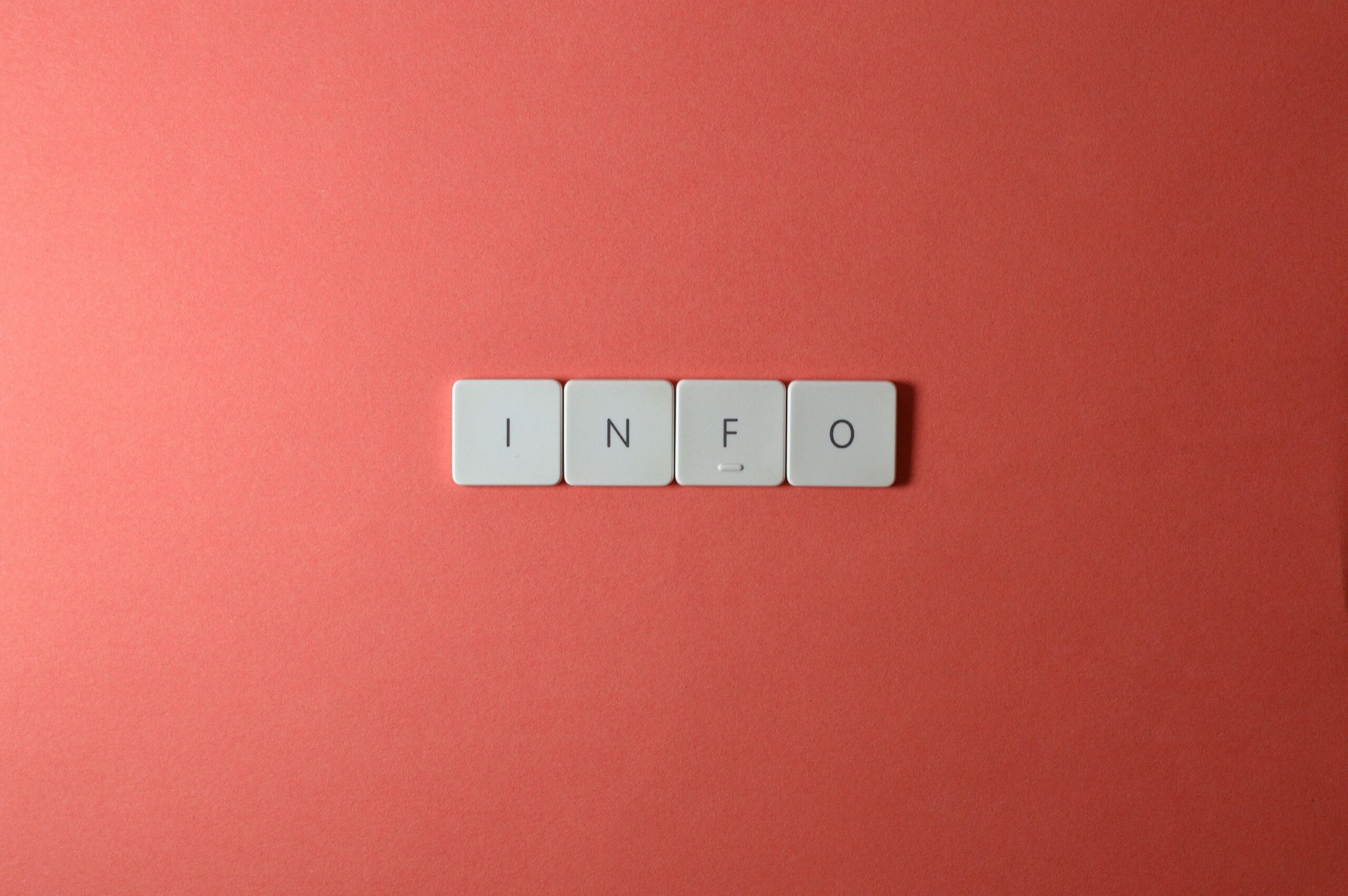 Close-up of keyboard buttons spelling 'INFO' on a minimal red background, ideal for tech and communication themes.